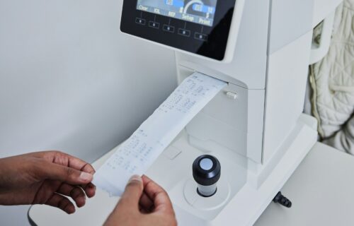 Ophthalmology, healthcare and printing with hands of person and machine for medical, information or